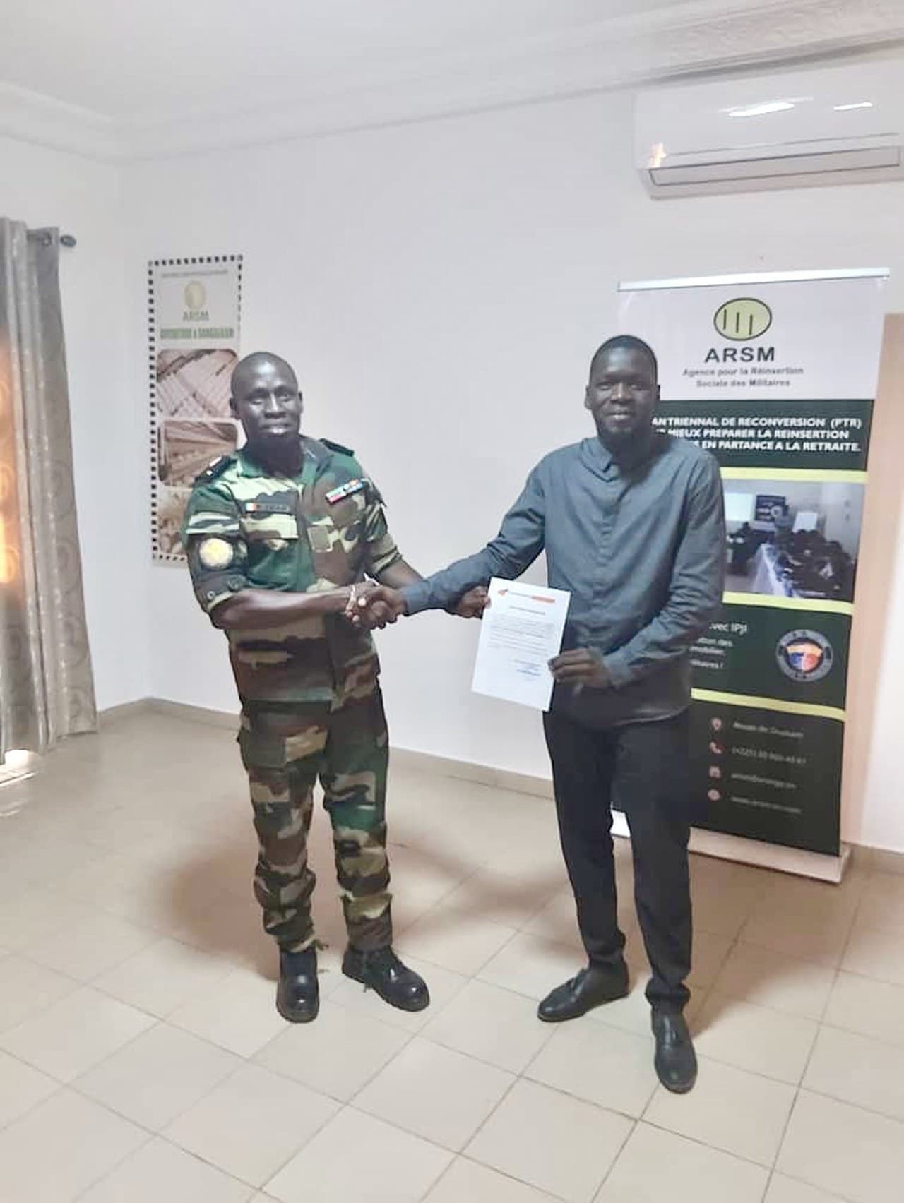 Remise de certificat à la fin de la formation RH-ARSM, devant le kakémono de l'Agence pour la Réinsertion Sociale des Militaires