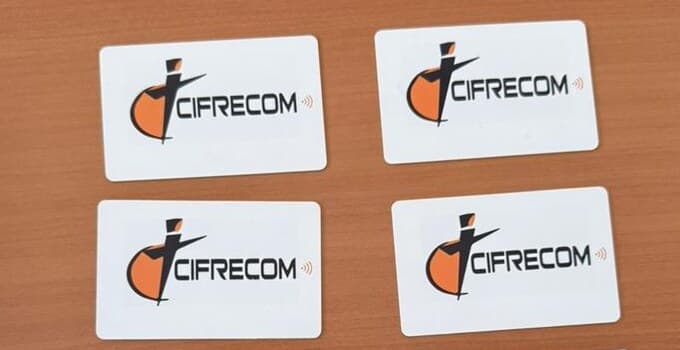 Quatre cartes de visite NFC Groupe IKARD aux couleurs de CIFRECOM, posées sur un bureau.